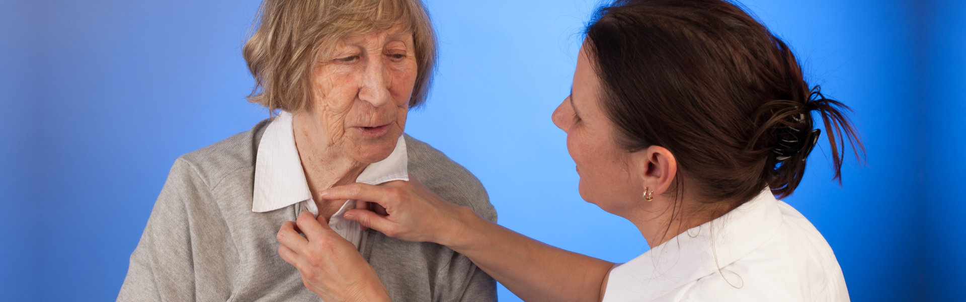 nurse dressing the elderly woman