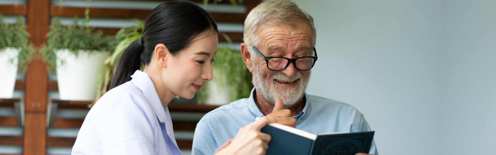 caregiver and elderly reading a book