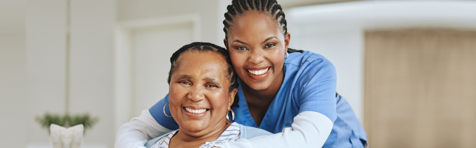 elderly and caregiver smiling and hugging